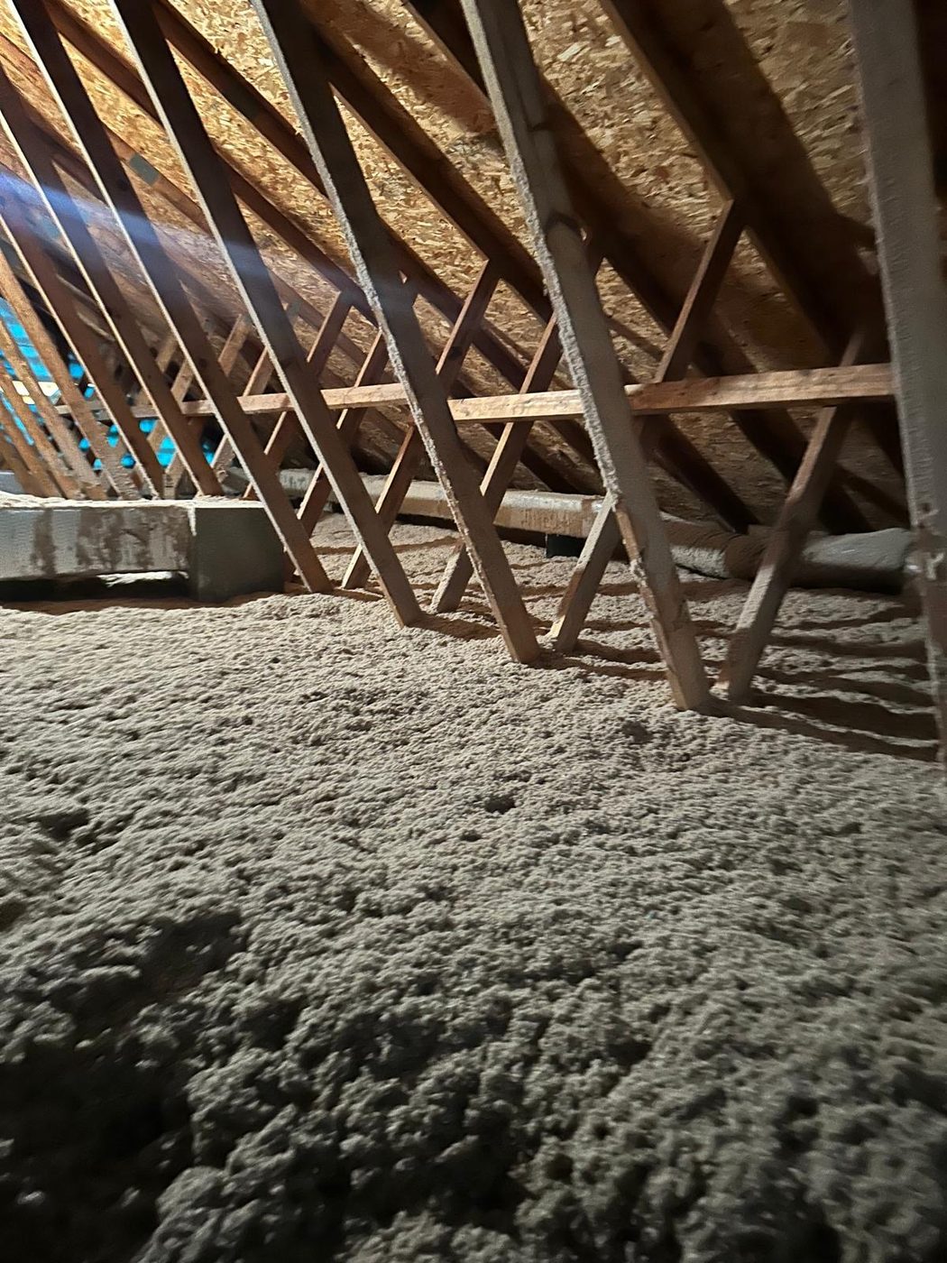 Attic space with wood roof trusses and blown-in insulation during an inspection