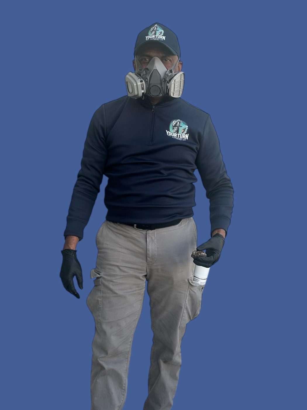 YourTurn Pest Solutions technician in company uniform, cap, respirator, and gloves, holding pest control equipment