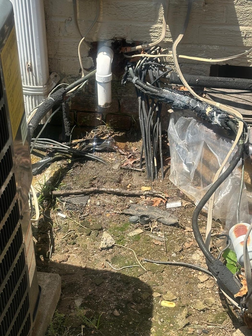 Exterior utility line penetration point at a home's foundation, next to an HVAC condenser unit